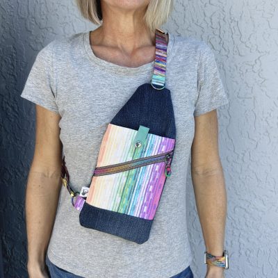 denim and multicolor stripe print mini travel sling with rainbow hardware