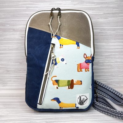 Front view of dog print canvas sling bag with colorful dachshund and puppy pattern – handmade crossbody backpack.